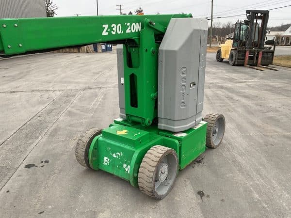 Green and Grey Genie Lift sitting in parking lot